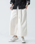 Clotechnow pale wide-leg hakama pants with a drawstring waist, styled with a black patterned shirt and white sneakers.
