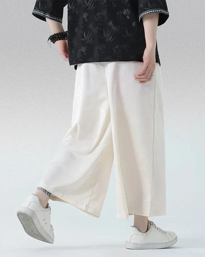 Clotechnow pale wide-leg hakama pants with a draped silhouette, styled with a black patterned top and white sneakers.