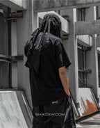 Dark graphic techwear tee showing a stylized pilot motif with cipher and circuit linework creating a futuristic streetwear look — view 4