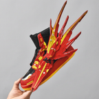 Red and yellow winged sneaker held by hand, studio close-up
