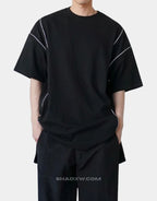 Black and white techwear t-shirt featuring a patterned light-responsive surface that brightens under illumination in urban styling — view 2