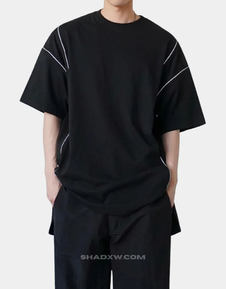 Black and white techwear t-shirt featuring a patterned light-responsive surface that brightens under illumination in urban styling — view 2