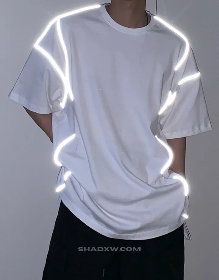 Black and white techwear t-shirt featuring a patterned light-responsive surface that brightens under illumination in urban styling — view 4