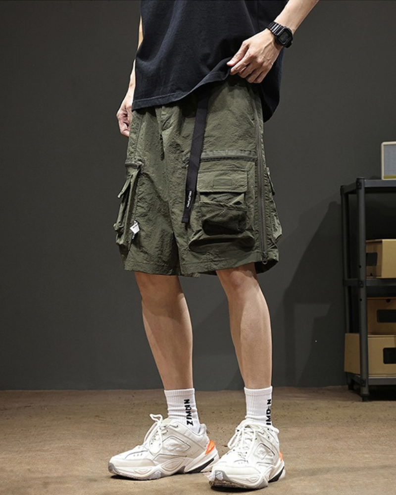 Person wearing green cargo shorts with a dark background
