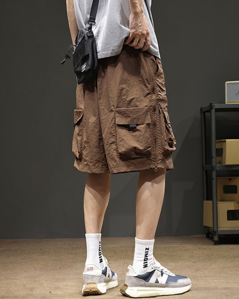 Person wearing brown cargo shorts with a plain background