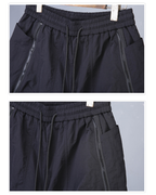 Black pants with drawstring waist and side zippers on a gray background