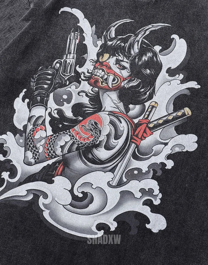 A close-up of a black t-shirt featuring a detailed graphic print of a Japanese demon with a katana and a revolver, surrounded by white waves. The brand name 'SHADXW' is printed in white at the bottom of the graphic.