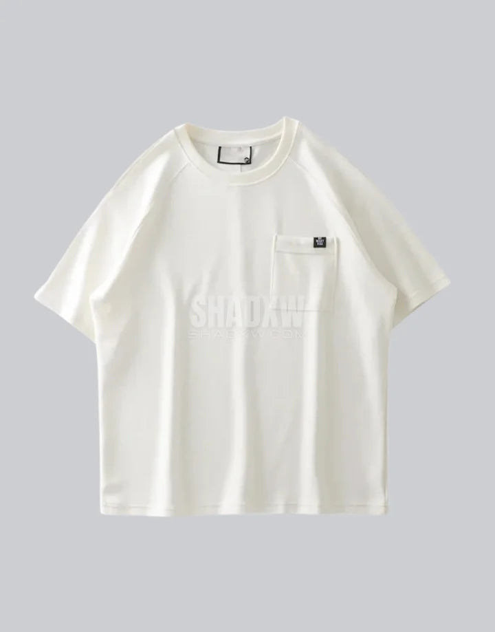 White short-sleeve techwear t-shirt with prominent black clip-closure front pocket and minimalist urban design details — view 2